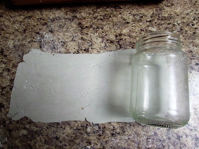 Place your jar on the flattened clay and with a sharp knife cut top and bottom evenly to cover the jar, leaving the twist part free to add the lid later.